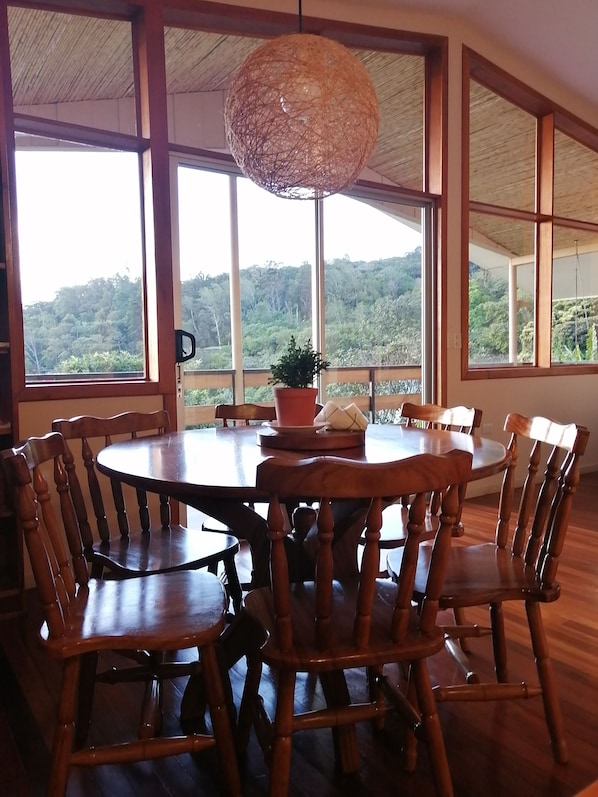 A round wooden dining table with chairs, large windows, and a hanging light fixture. - Perfect house for friends and family in Monteverde (Monteverde)