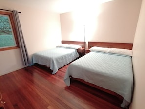 A room with two beds, wooden flooring, and a window with curtains. - Perfect house for friends and family in Monteverde (Monteverde)