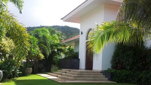 Una casa con fachada blanca, techo de tejas rojas y una entrada frontal con escalones.