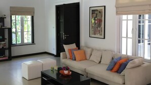 Un salón amplio con un sofá beige grande, una mesa de centro negra y una estantería.