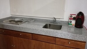 Cocina con encimera de granito, pileta de acero inoxidable y muebles de madera.