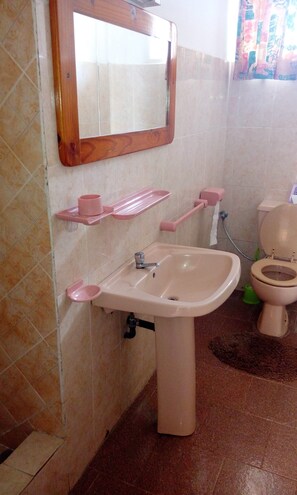 A bathroom with a sink, mirror, toilet, and pink accessories.