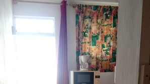 A small kitchen with a microwave, a refrigerator, and a bench. - Airconditioned room wit kitchnette ideal for individual, family and groups. (Grand Bay)