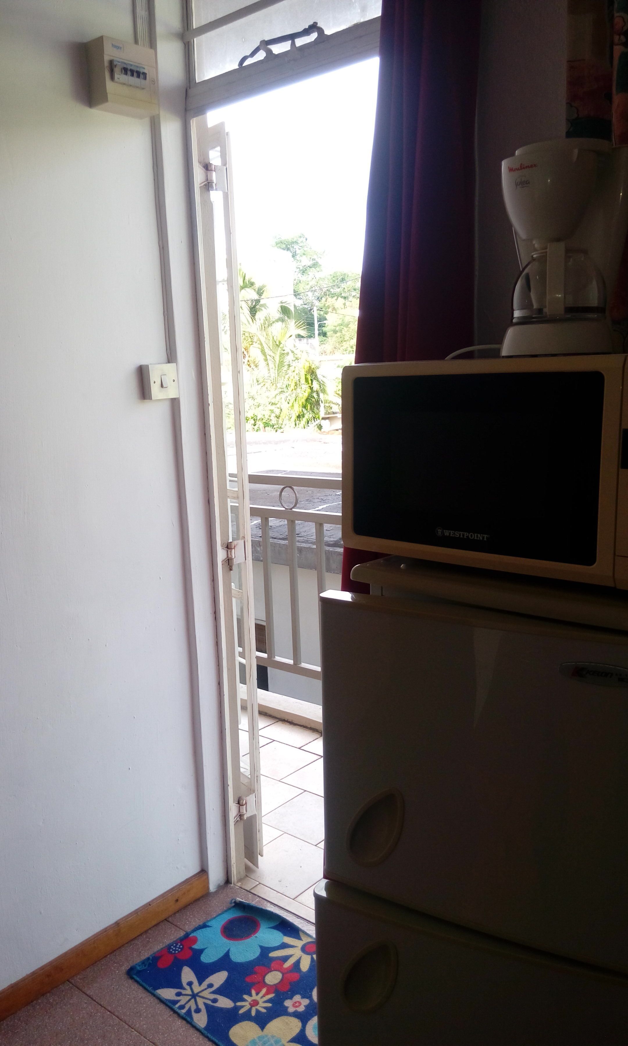 Una cocina con microondas, cafetera y ventana con vistas al exterior.