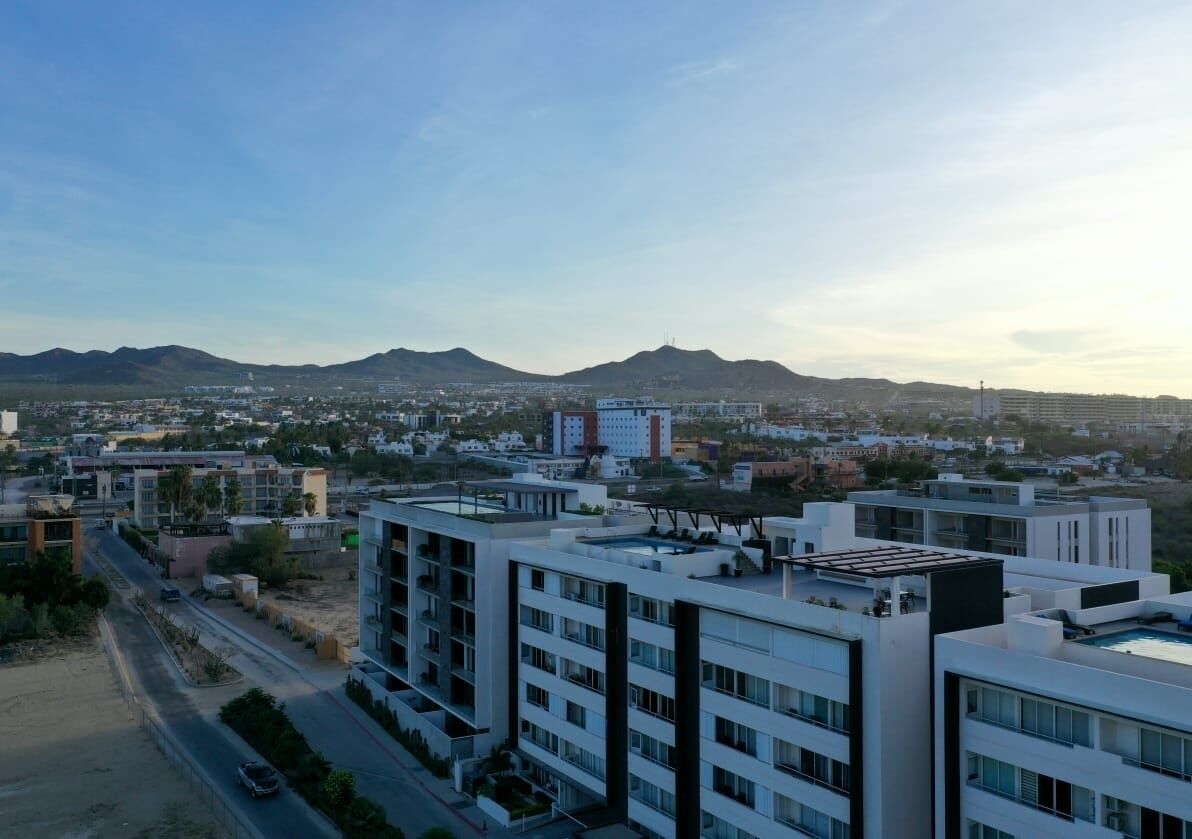 A modern urban landscape with high-rise buildings, a clear sky, and distant mountains.