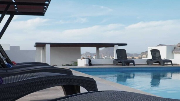 Un espace aménagé au bord de la piscine, avec des chaises longues et une vue sur une chaîne de montagnes.