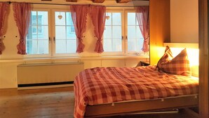 A bedroom with a wooden ceiling, a bed with a checkered bedspread, and a window with checkered curtains. - CHALET AU SWISS style (Zürich)