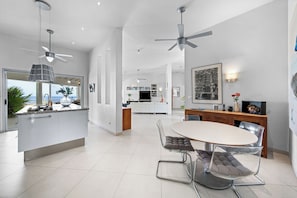 Une cuisine moderne dotée d’un îlot central, d’un coin repas avec une table ronde et des chaises, et d’un ventilateur de plafond.