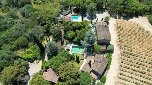 An aerial view of a property with a swimming pool, multiple buildings, and a vineyard.
