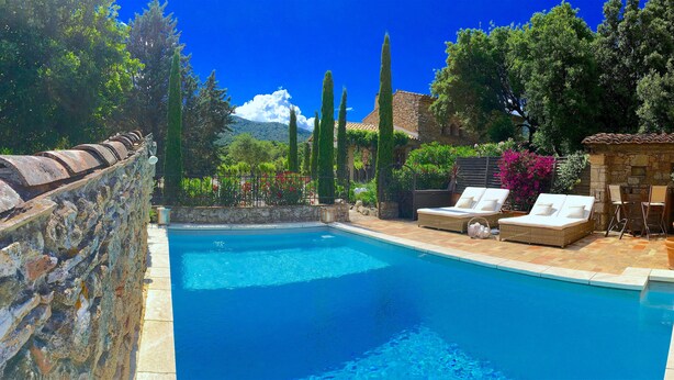 A swimming pool with lounge chairs and a stone wall.