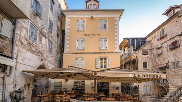 Un bâtiment appelé « Plaza Marchi », doté d’une terrasse et d’une enseigne indiquant « LA BODEGA ».