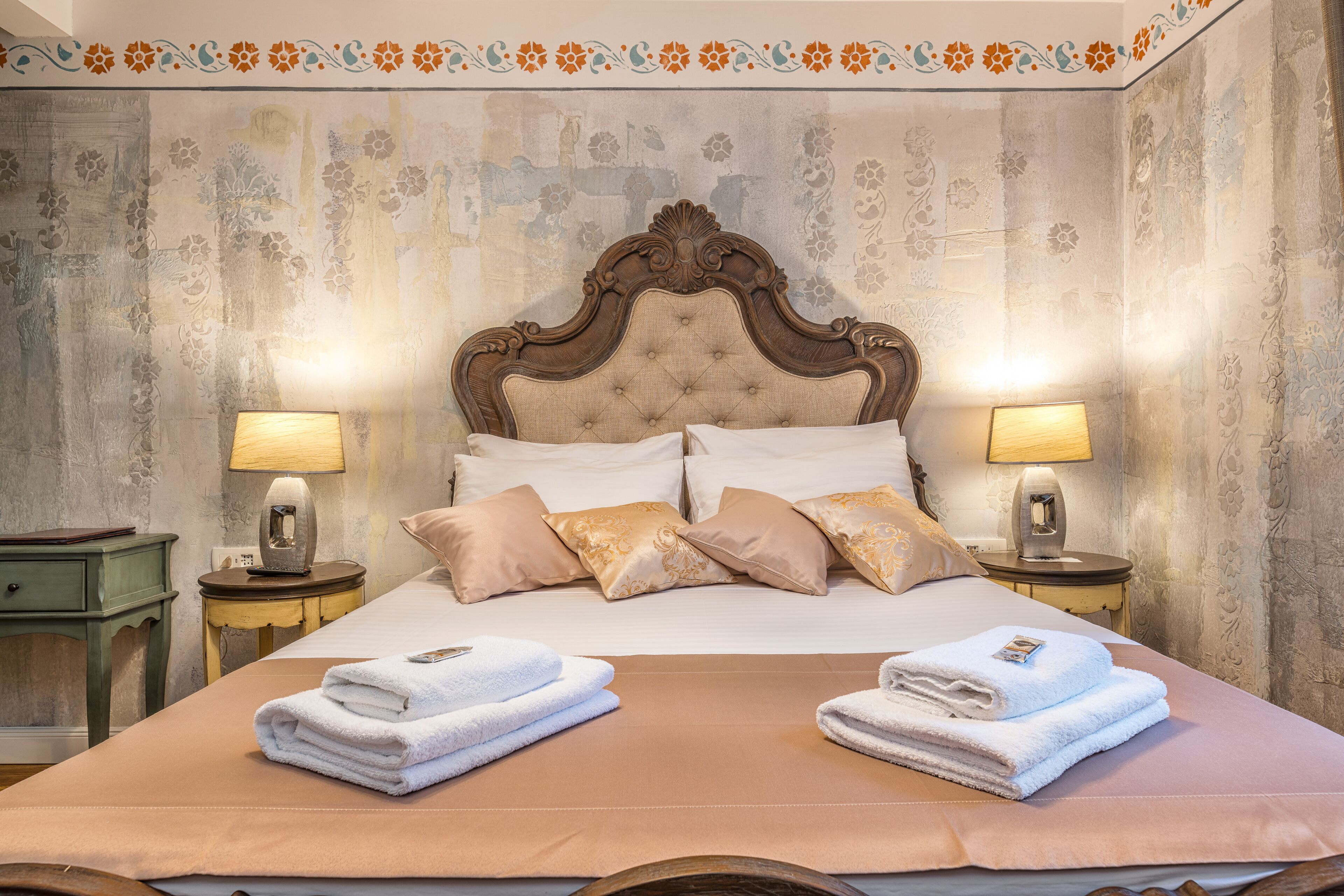 Une chambre d’hôtel avec un grand lit, deux tables de chevet avec des lampes et une tête de lit décorative.