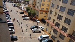 Useita kerroksia sisältävä pysäköintihalli, jossa on useita parkkeerattuja ajoneuvoja ja jalankulkijoita.