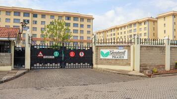 A gated entrance to a building with multiple floors, a sign indicating a 5kph speed limit for children playing, and a sign for 'Greatwall Apartments Phase II'.