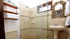 Une salle de bain avec une douche à parois de verre, des toilettes, un lavabo et un miroir doté d’un cadre décoratif.
