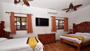 Une chambre d’hôtel avec deux lits, une télévision, des ventilateurs de plafond et une commode en bois.