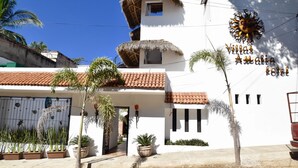 Un bâtiment blanc surmonté d’un toit recouvert de tuiles rouges, une enseigne indiquant « Hôtel Villas Andalusia » et plusieurs plantes en pot.