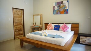 Relax in a cozy space with a large, neatly made bed and a variety of pillows, including a decorative one with an embroidered design.
