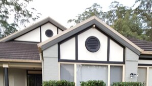 Un edificio de dos pisos con techo plano, entrada principal y un pequeño porche.