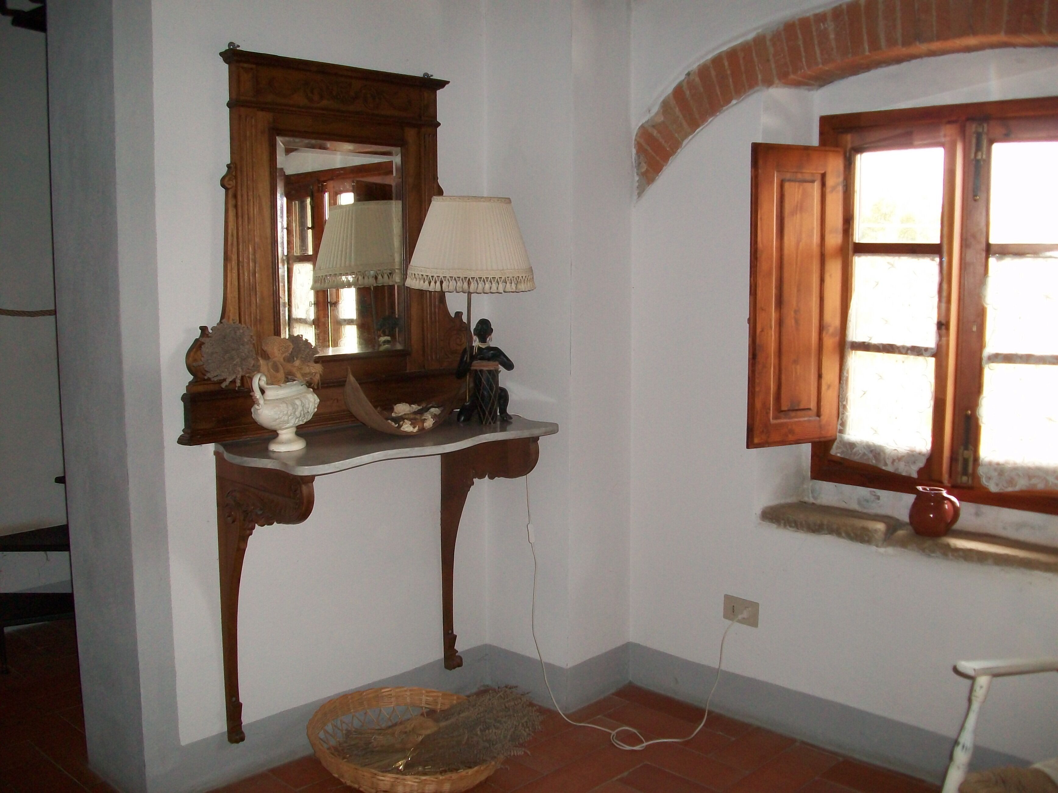Une pièce avec une coiffeuse en bois, un miroir, une lampe et une fenêtre donnant sur un beau paysage.