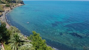 Vista costera con mar azul cristalino, costa rocosa y vegetación.
