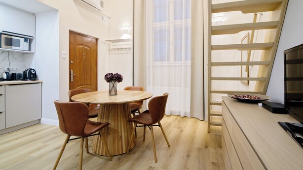 Een moderne keuken met een magnetron, koffiezetapparaat en een eethoek met een houten tafel en stoelen.
