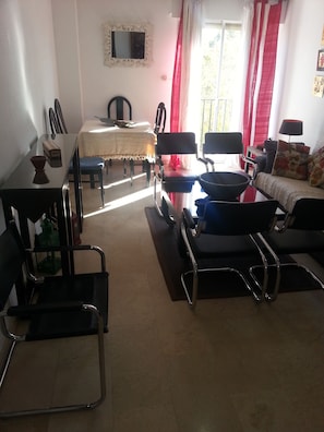 Una sala de estar con una mesa de comedor, sillas, un sofá y un televisor.