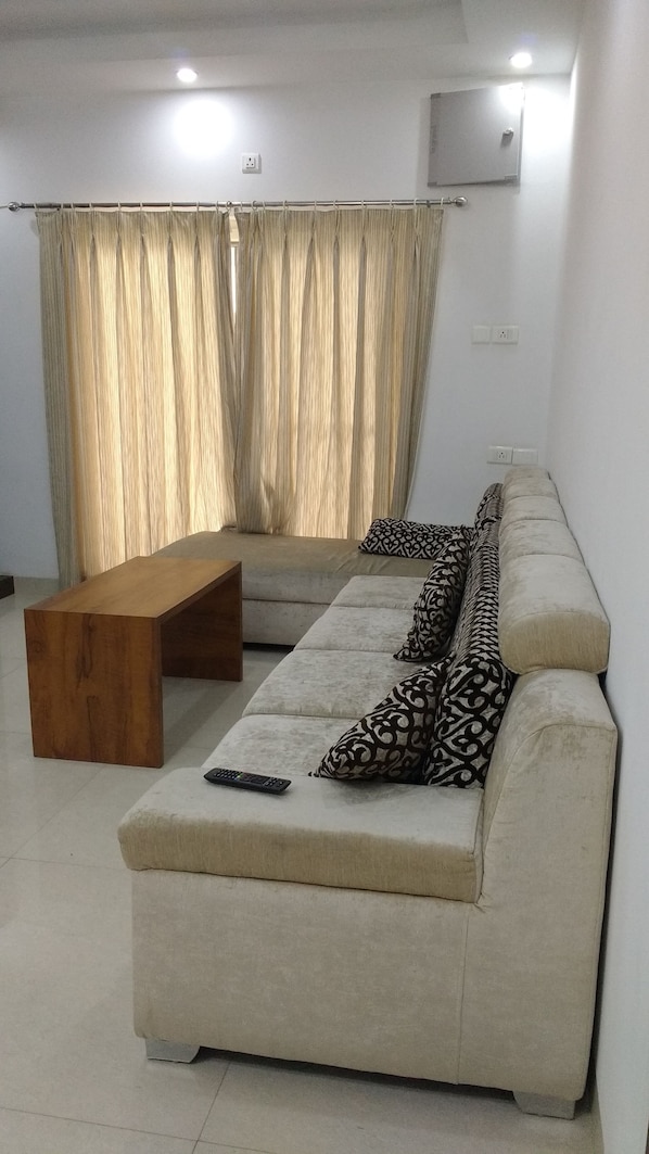 A living room with a beige sofa, a wooden coffee table, and patterned cushions.