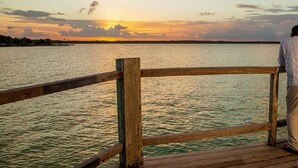 A wooden pier with a railing overlooking a body of water during sunset. - Cozy Two Twin Bed Suite (Orchid Bay)