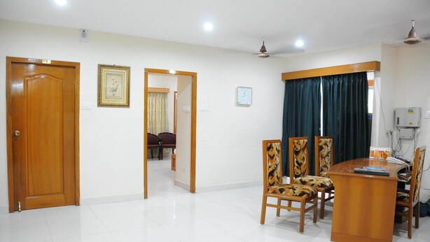 A dining area with a wooden table and chairs, a ceiling fan, and a clock on the wall.
