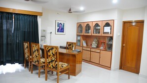 A dining area with a wooden table and chairs, a cabinet with decorative items, and a door.