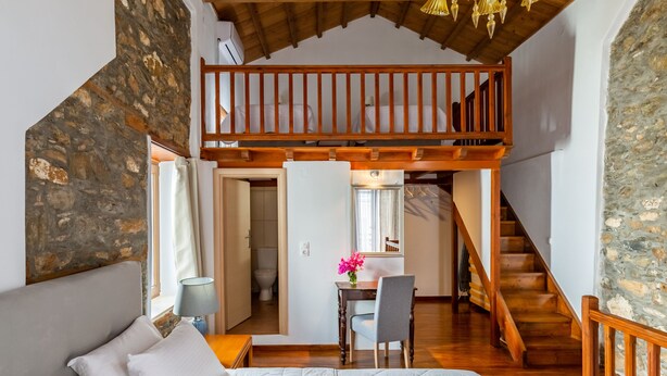 A bedroom with a bed, a desk, and a staircase leading to an upper level. - Large Villa for nine people (Skopelos Town, Skopelos Island)