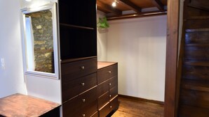 A room with a wooden dresser, a mirror, and a stone wall. - Large Villa for nine people (Skopelos Town, Skopelos Island)