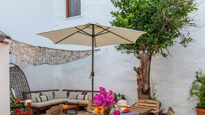 A patio with a round wooden table, six chairs, a beige umbrella, and potted plants. - Large Villa for nine people (Skopelos Town, Skopelos Island)