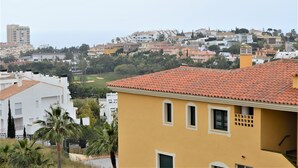 Una zona residencial con un edificio amarillo en primer plano, edificios blancos al fondo y un paisaje montañoso.