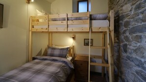 Habitación con literas, una escalera de madera, una mesita de noche y una ventana pequeña.