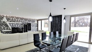 A modern dining area with a glass table, black chairs, and a patterned wall. - Beautiful house ideal for relaxation (Bela Monção)