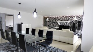 A modern living room with a glass dining table, black chairs, a white sofa, and a patterned wallpaper. - Beautiful house ideal for relaxation (Bela Monção)
