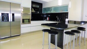 A modern kitchen with a central island, stainless steel appliances, and bar stools. - Beautiful house ideal for relaxation (Bela Monção)