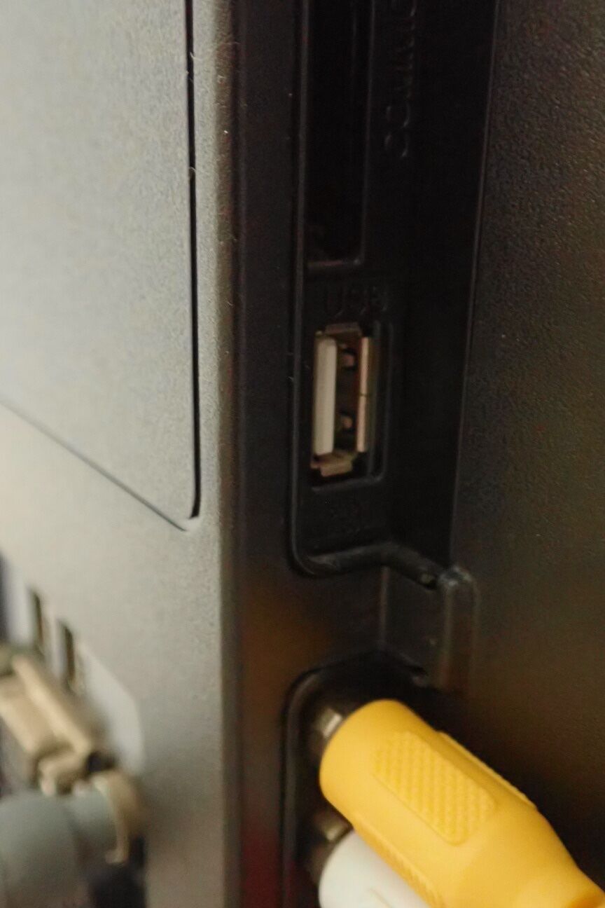 Detalle del interior de un vehículo, mostrando un puerto USB y un asa amarilla.