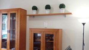 Una habitación con armarios de madera, un florero de vidrio y una estantería con plantas en macetas.
