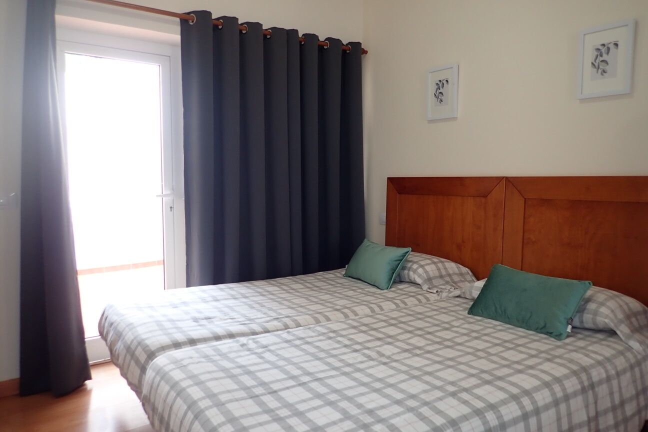 A bedroom with two beds, a wooden headboard, and a view of the outdoors.