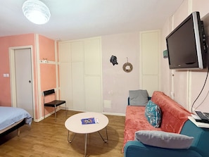 Una stanza con un letto, un divano, un tavolo, una TV e un armadio.