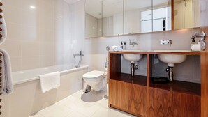 Ein modernes Badezimmer mit Badewanne, Toilette und einem doppelten Waschtisch.