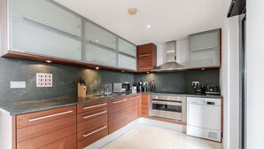 Eine moderne Küche mit Holzschränken, Edelstahlgeräten und einer Arbeitsplatte aus Granit.
