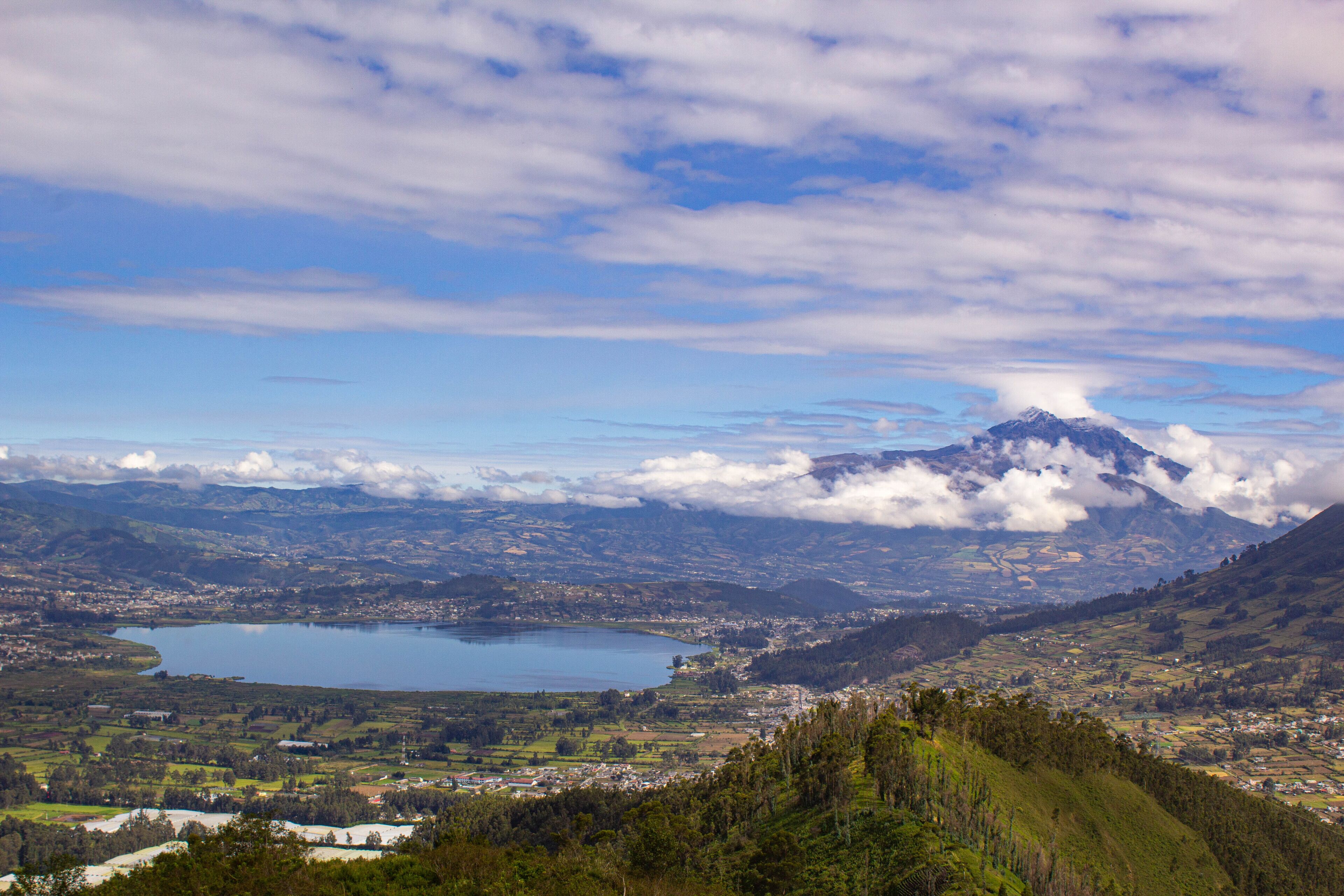Un paysage montagneux avec un lac, une ville et un sommet imposant.