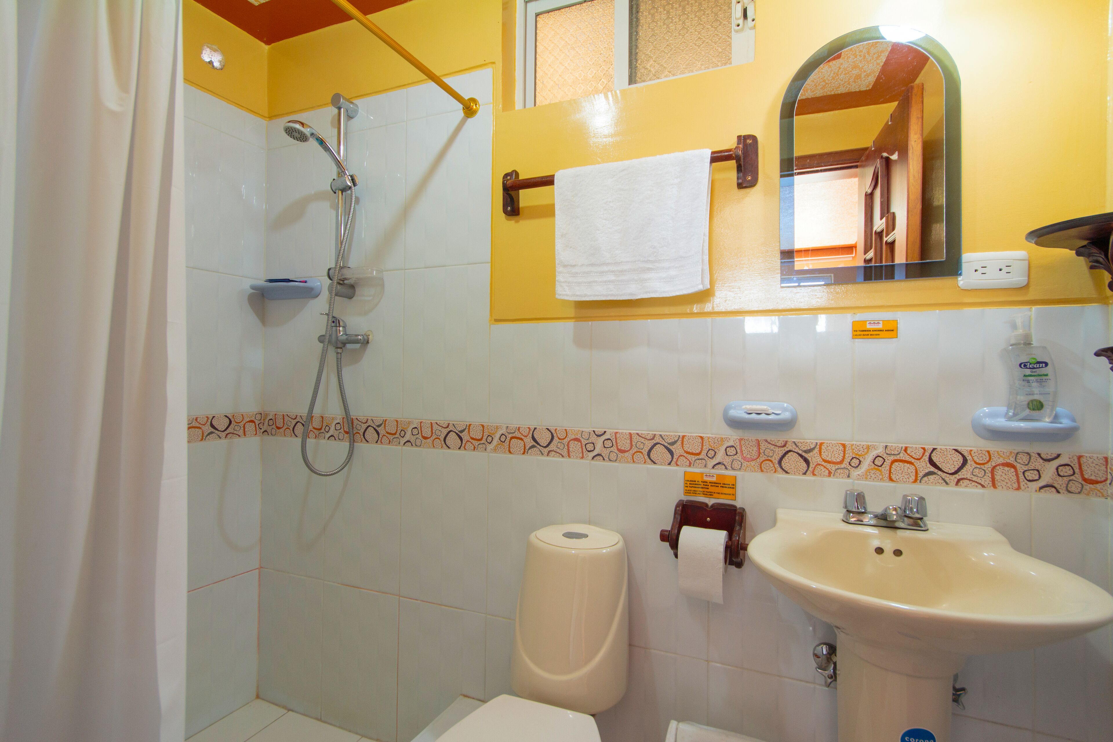 Une salle de bain équipée d’une douche, de toilettes, d’un lavabo et d’un miroir.