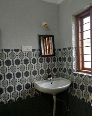 Bathroom features a sink and mirror, surrounded by a patterned tile design and a window.