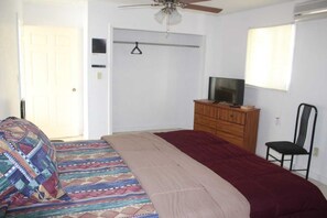 Une chambre à coucher avec un lit, une commode en bois, un téléviseur et une chaise.