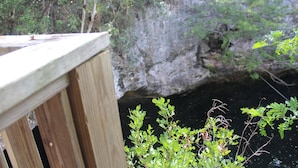 Une terrasse en bois surplombe une falaise rocheuse, avec une étendue d’eau en contrebas.